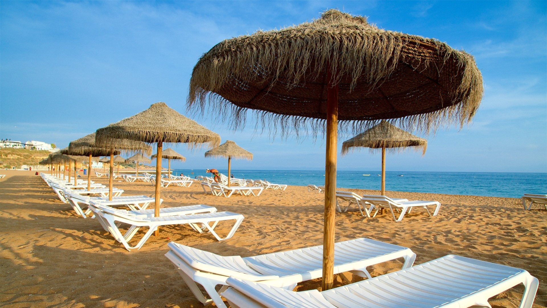 Guarda-sóis de colmo e espreguiçadeiras na praia em Albufeira