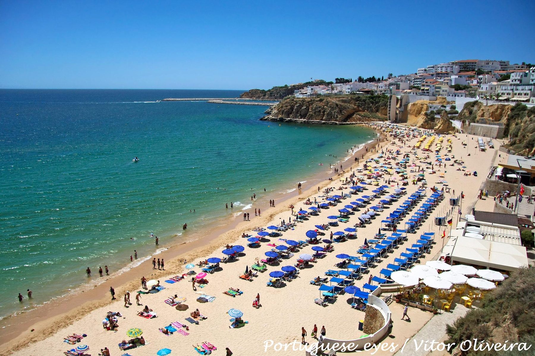 Praia do Peneco, em Albufeira, com chapéus de sol azuis e o mar turquesa